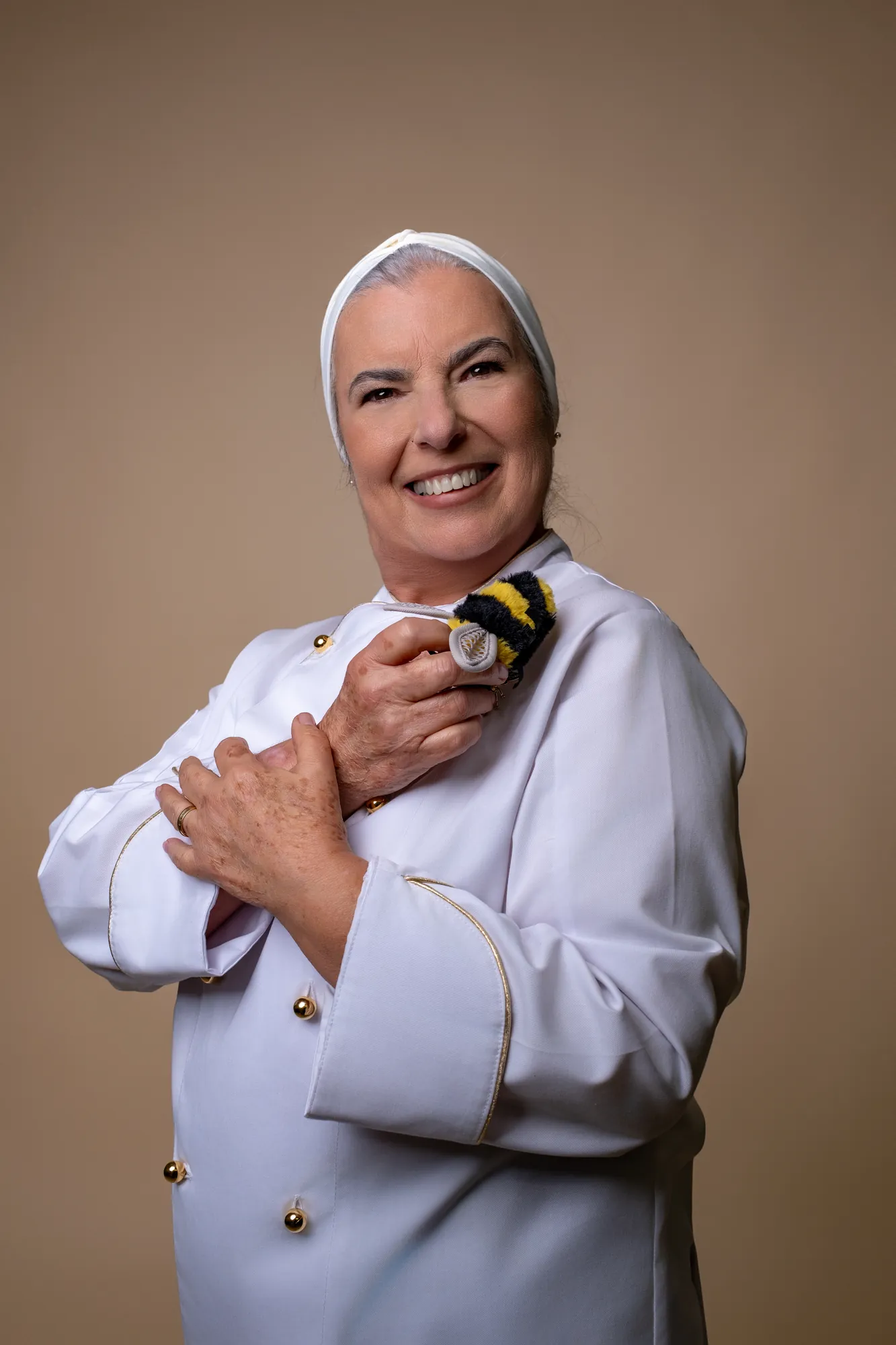 Miria Paula de dólman branco, com a mão no peito, a sorrir