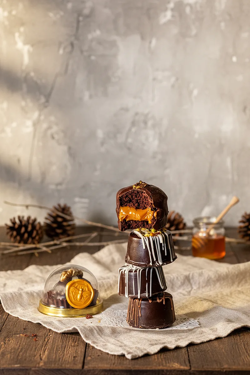 Pão de mel banhado em chocolate, com mel e pinhas ao lado