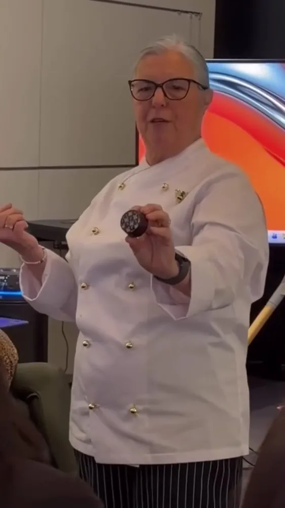 Miria Paula de dólman branco a ensinar no Workshop Mel, com um pão de mel na mão